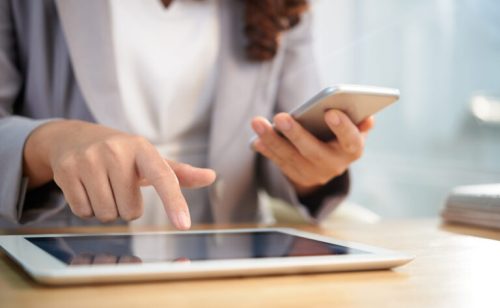 Hands of business woman using digital tablet and smartphone in work