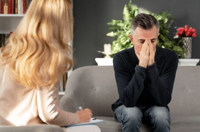 mid-shot-man-sitting-couch-therapy-cabinet-near-therapist